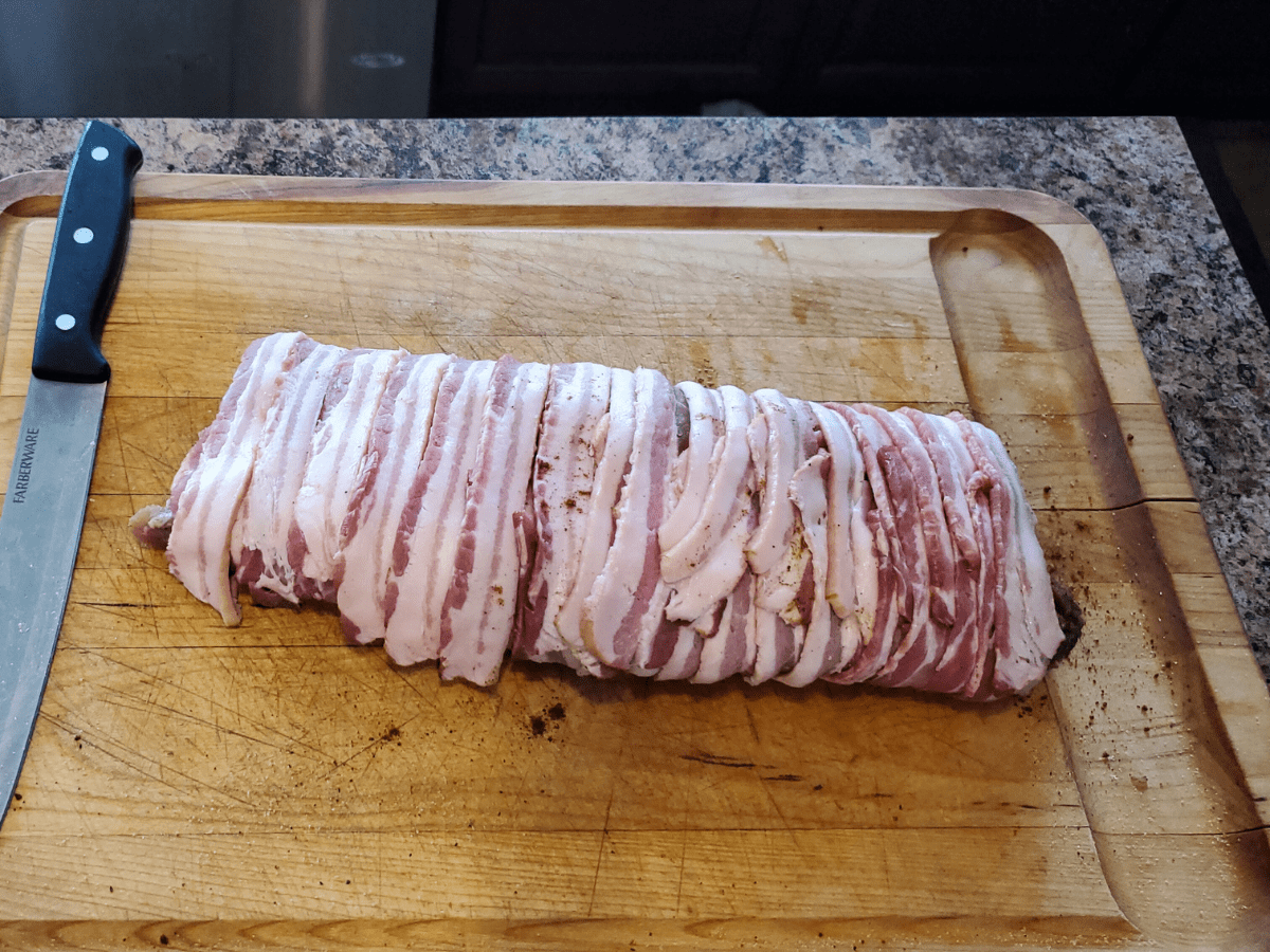 smoked pork tenderloin wrapped in bacon wrapped on a cutting board